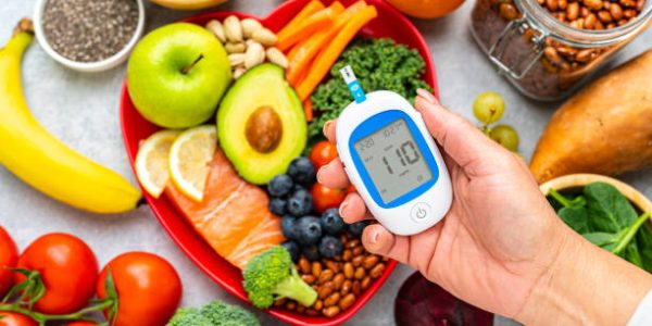 diabetes Hand holding glucometer on healthy food background. High resolution 42Mp studio digital capture taken with SONY A7rII and Zeiss Batis 40mm F2.0 CF lens